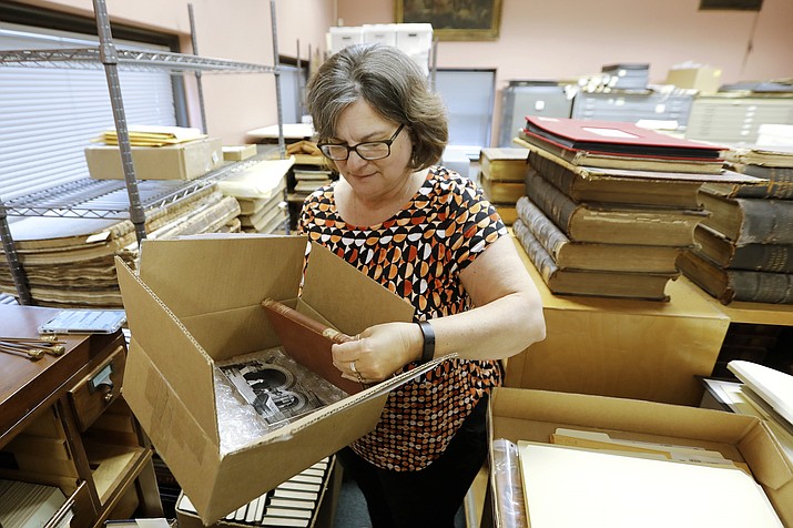 New Bedford Public Library Director Olivia Melo, pulls the 100 year overdue book from the box shipped to New Bedford, Mass., from West Virginia University Library on Friday, July 7, 2023. "An Elementary Treatise on Electricity" by James Clerk Maxwell was returned to the West Virginia University library one hundred years after it was taken out of the New Bedford Public library in 1903. (Peter Pereira/The Standard-Times via AP)