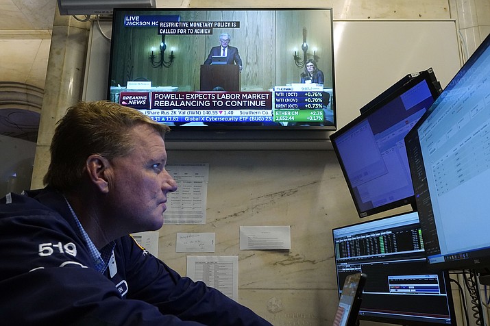 Trader John Bowers works on the floor of the New York Stock Exchange, Friday, Aug. 25, 2023, as Federal Reserve Chair Jerome Powell's speech shows on a television screen. Stocks are holding on to gains after Powell said more rate hikes could be on the way to continue the Fed's fight against inflation. (Richard Drew/AP)