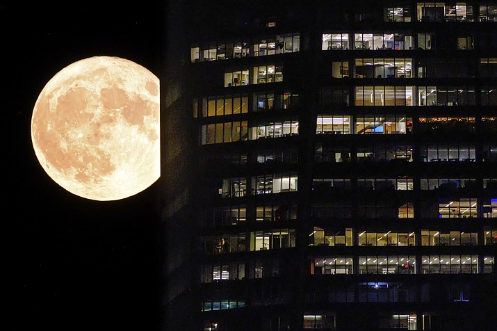 A supermoon passes behind the illuminated windows of a New York City skyscraper, Aug. 1, 2023. A rare blue supermoon could normal raise tides just as Hurricane Idalia takes aim at Florida’s west coast, exacerbating flooding from the storm. The moon will be closest to the Earth on Wednesday night, Aug. 30, the same day Idalia is expected to make landfall in Florida. (J. David Ake/AP, File)